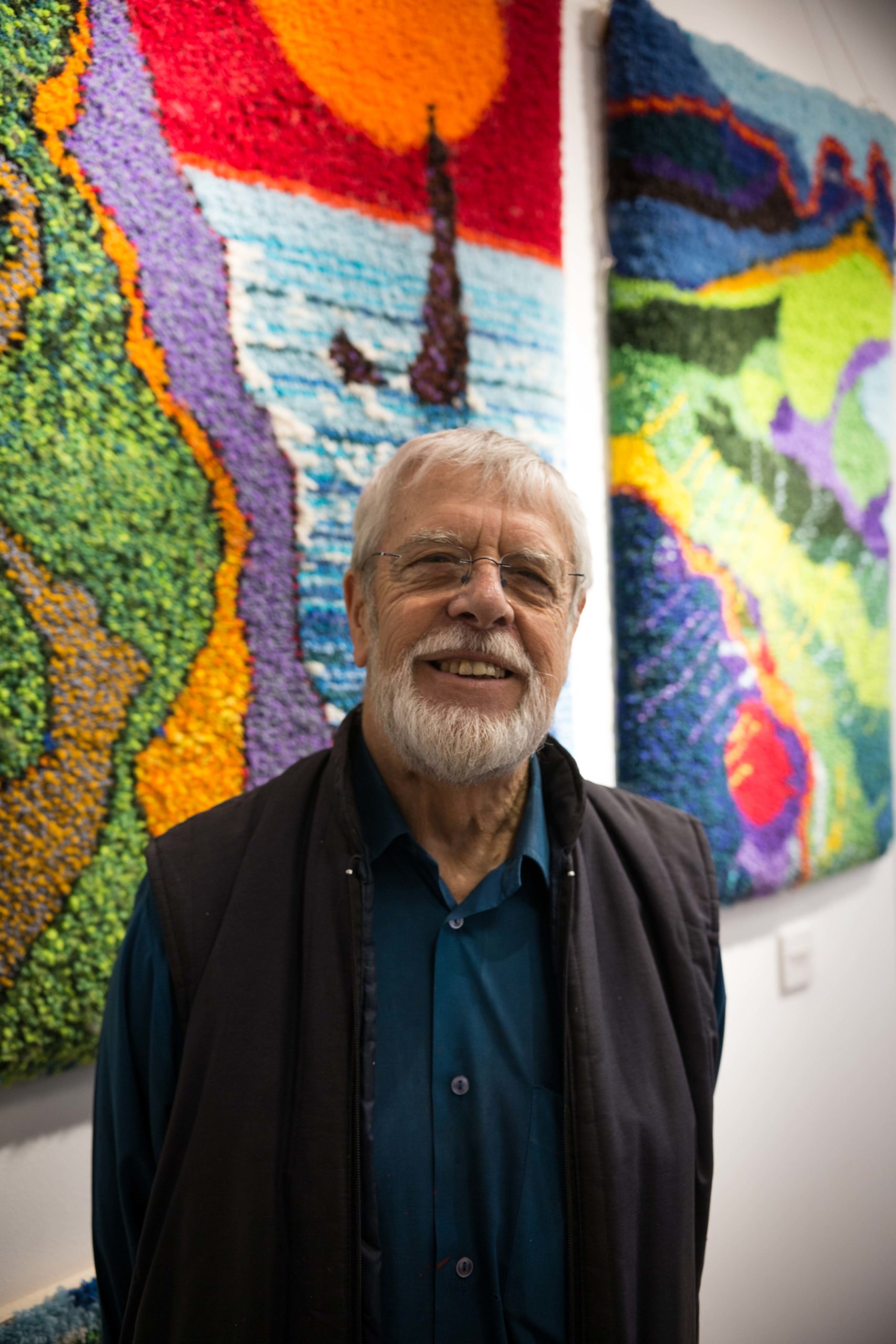 Keith Gretton standing in front of his colourful knotted rug