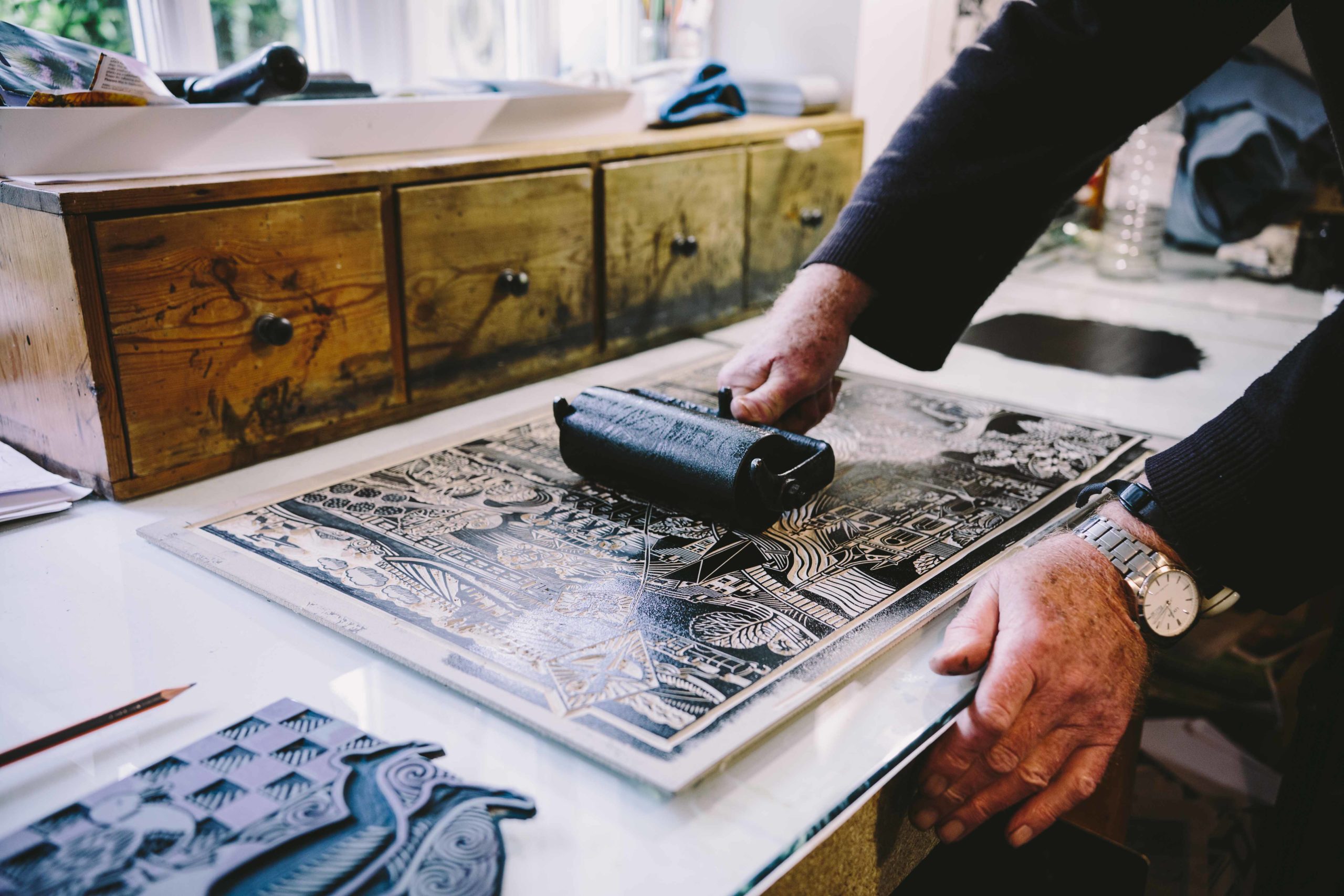 Hugh Ribbons hands rolling ink onto a lino cut